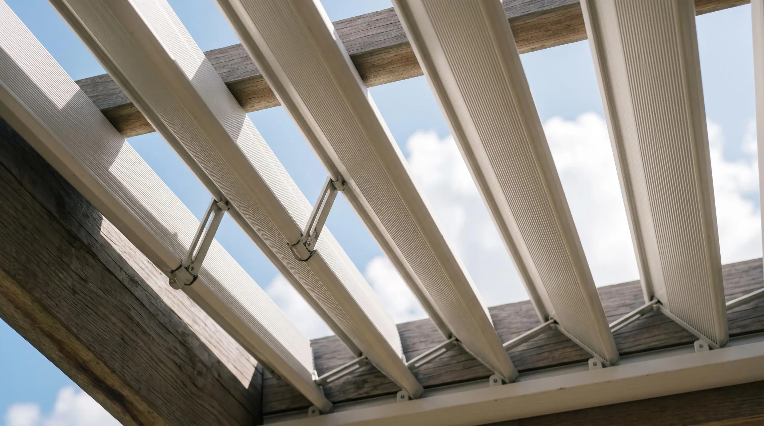 Gros plan sur les lames orientables en aluminium d'une pergola bioclimatique en position partiellement ouverte
